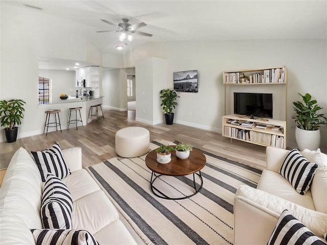 living room featuring lofted ceiling, ceiling fan, and light wood-type flooring