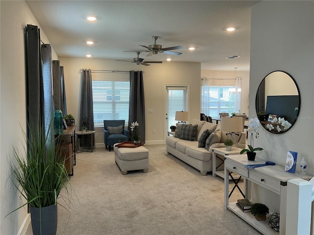 carpeted living room with ceiling fan with notable chandelier