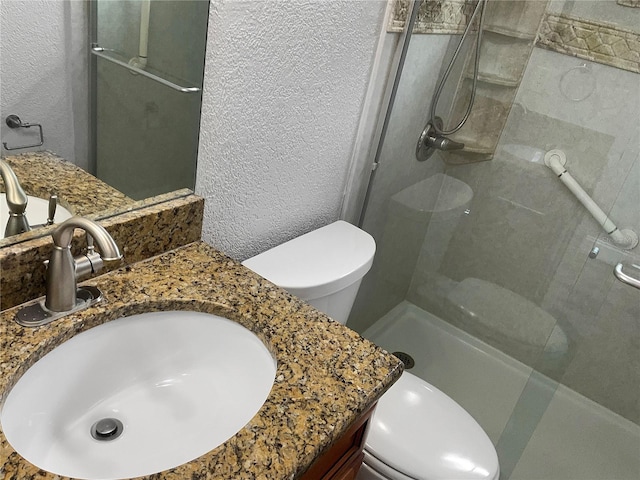 bathroom featuring vanity, a shower with shower door, and toilet