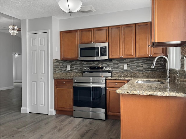 kitchen featuring sink, stainless steel appliances, light stone counters, and backsplash