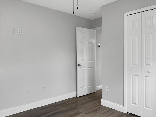 unfurnished bedroom with a closet and dark hardwood / wood-style floors