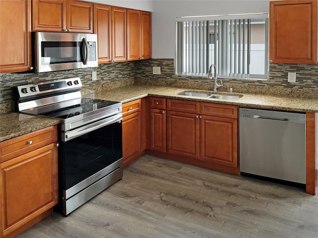 kitchen featuring sink, wood-type flooring, stone counters, and stainless steel appliances