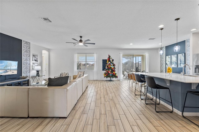 living room with sink, a textured ceiling, and ceiling fan