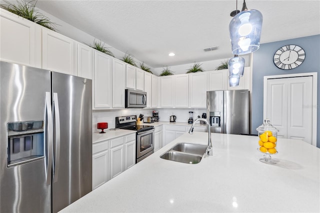 kitchen featuring appliances with stainless steel finishes, sink, decorative light fixtures, backsplash, and white cabinets