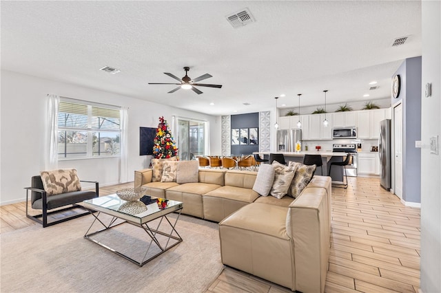 living room with ceiling fan and a textured ceiling