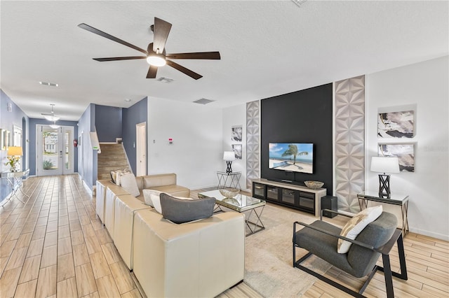 living room featuring ceiling fan and a textured ceiling