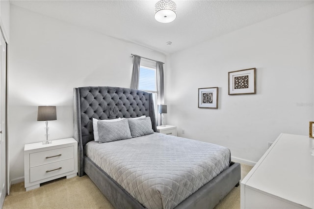 bedroom featuring light colored carpet and a textured ceiling