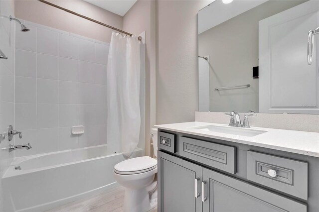 full bathroom featuring shower / tub combo with curtain, vanity, hardwood / wood-style flooring, and toilet