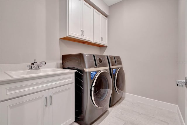 washroom featuring cabinets, sink, and washer and dryer