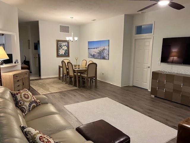 living room featuring hardwood / wood-style flooring and ceiling fan with notable chandelier