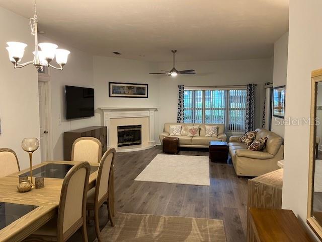 living room with dark wood-type flooring and ceiling fan with notable chandelier