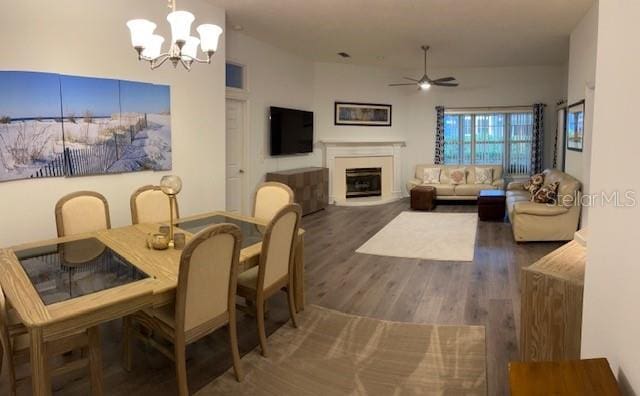 dining room featuring ceiling fan with notable chandelier and dark hardwood / wood-style flooring