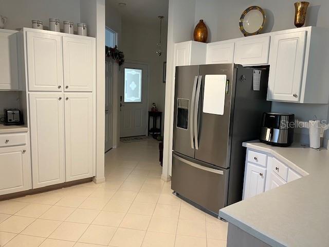 kitchen featuring stainless steel refrigerator with ice dispenser, white cabinetry, and light tile patterned floors