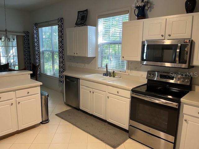 kitchen featuring sink, white cabinetry, hanging light fixtures, and appliances with stainless steel finishes