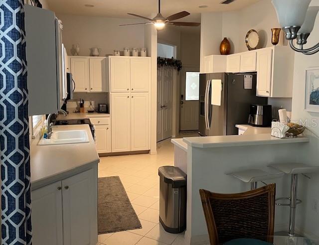 kitchen featuring ceiling fan, white cabinetry, stainless steel refrigerator with ice dispenser, and light tile patterned flooring