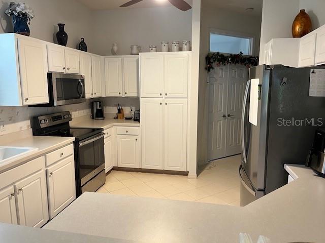 kitchen with white cabinets, light tile patterned floors, and appliances with stainless steel finishes