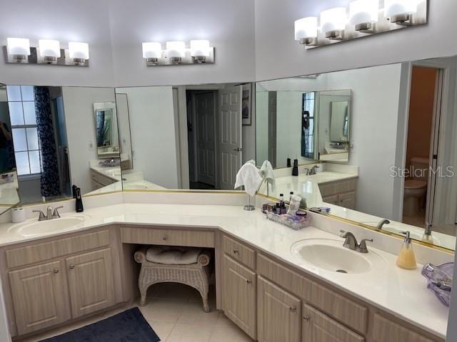 bathroom with toilet, vanity, and tile patterned flooring