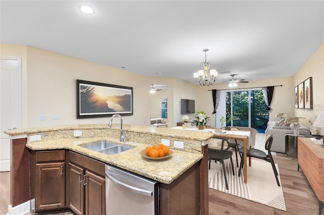 kitchen featuring dark brown cabinets, stainless steel dishwasher, sink, hardwood / wood-style flooring, and a center island with sink