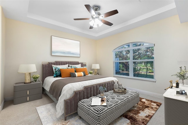 bedroom with ceiling fan, a raised ceiling, and light carpet