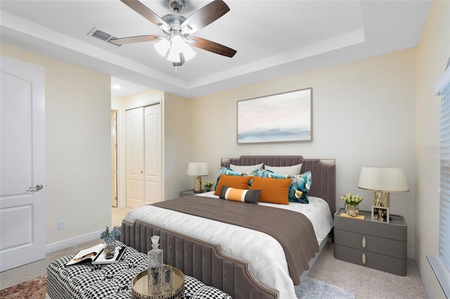 carpeted bedroom featuring a closet, ceiling fan, and a raised ceiling