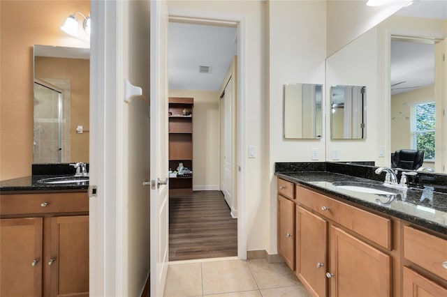 bathroom with tile patterned flooring, walk in shower, and vanity