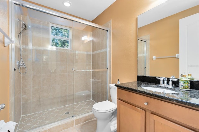 bathroom featuring toilet, a shower with shower door, tile patterned floors, and vanity