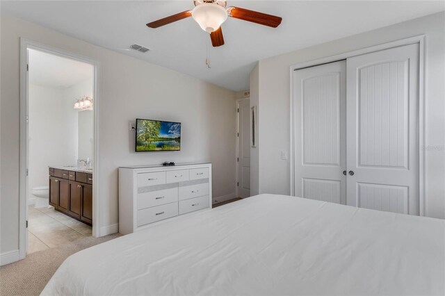 carpeted bedroom with ceiling fan, ensuite bathroom, sink, and a closet