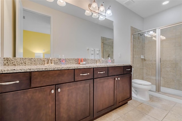 bathroom featuring tile patterned flooring, vanity, a shower with shower door, and toilet