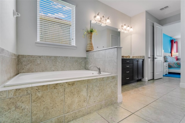 bathroom featuring tiled tub, vanity, and tile patterned floors