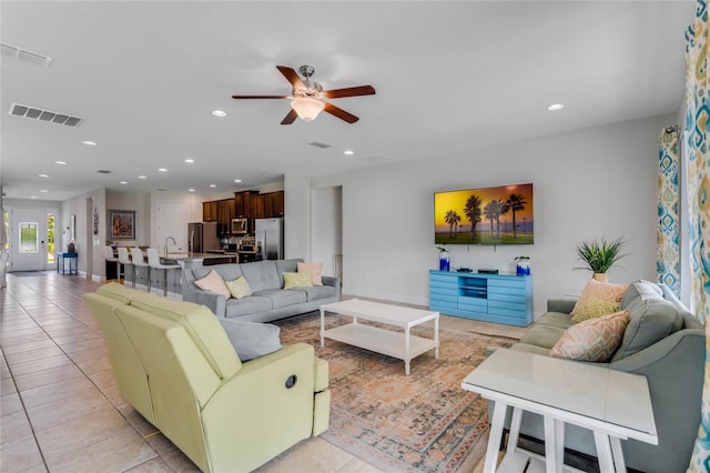 living room featuring ceiling fan, sink, and light tile patterned floors