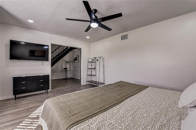 bedroom with ceiling fan, a textured ceiling, and hardwood / wood-style flooring