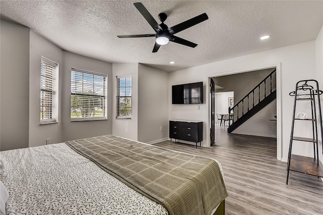 bedroom with ceiling fan, hardwood / wood-style floors, and a textured ceiling