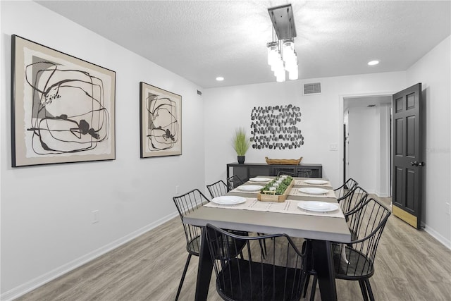 dining space with a textured ceiling and light wood-type flooring