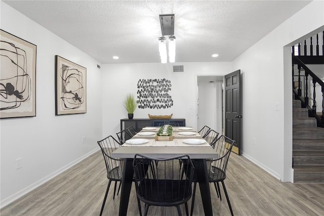 dining space with a textured ceiling and light hardwood / wood-style flooring