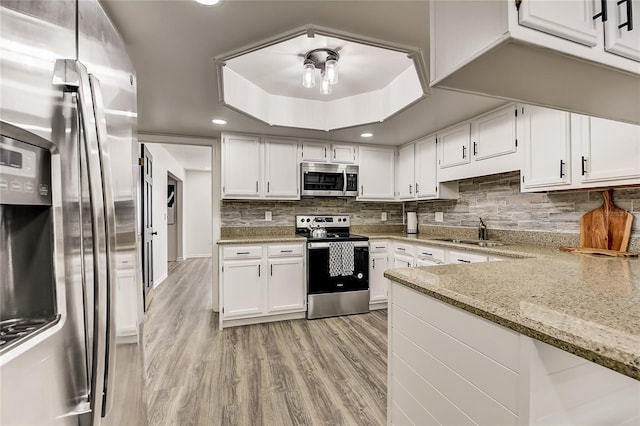 kitchen with white cabinets, light stone counters, and appliances with stainless steel finishes