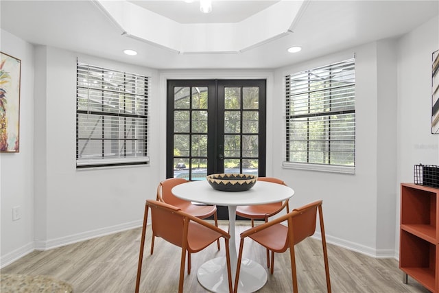 dining space featuring french doors, light hardwood / wood-style floors, and a tray ceiling