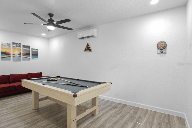 recreation room with a textured ceiling, wood-type flooring, billiards, ceiling fan, and a wall mounted air conditioner