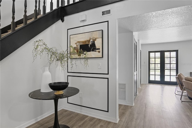 interior space with wood-type flooring, a textured ceiling, and french doors