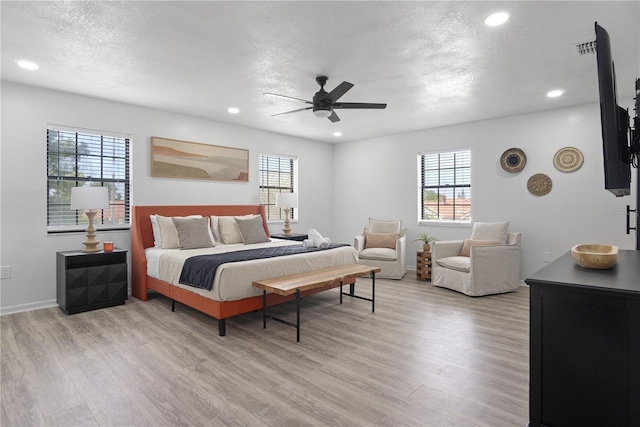 bedroom featuring ceiling fan, light hardwood / wood-style flooring, and a textured ceiling