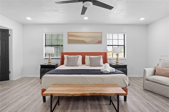 bedroom featuring light hardwood / wood-style floors, a textured ceiling, multiple windows, and ceiling fan