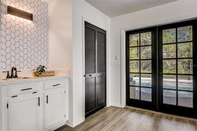 doorway to outside with light hardwood / wood-style floors, sink, a textured ceiling, and french doors