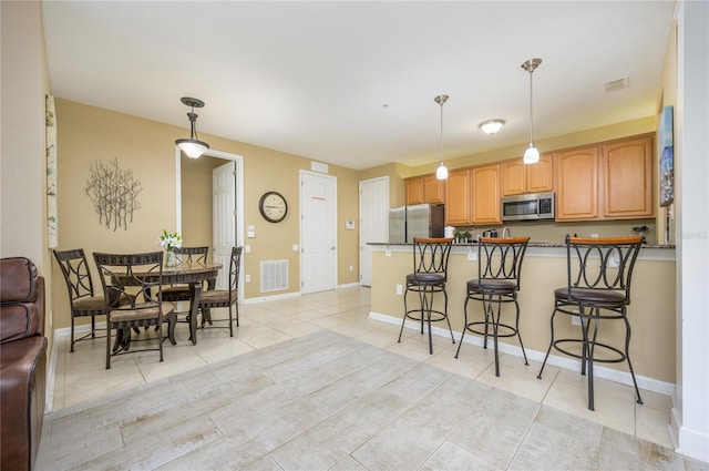 5012 Shoreway Loop Unit 10207, Orlando, FL 32819 - kitchen with stainless steel appliances, light tile patterned flooring, a peninsula, a breakfast bar area, and pendant lighting