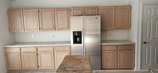 kitchen featuring light tile patterned floors, tile countertops, stainless steel fridge with ice dispenser, and light brown cabinetry