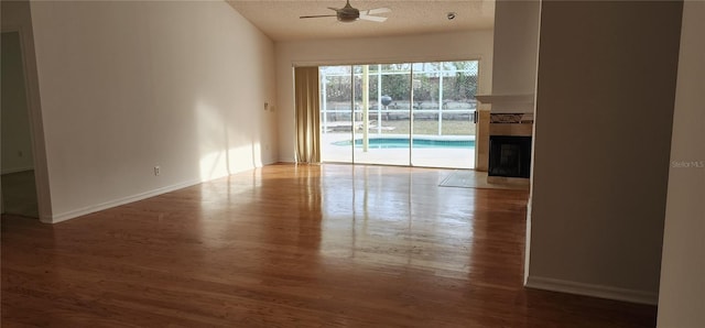 unfurnished living room with ceiling fan, a textured ceiling, hardwood / wood-style flooring, and a fireplace