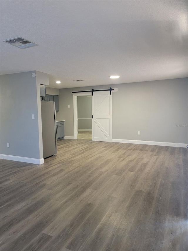 unfurnished living room featuring hardwood / wood-style floors, a textured ceiling, and a barn door