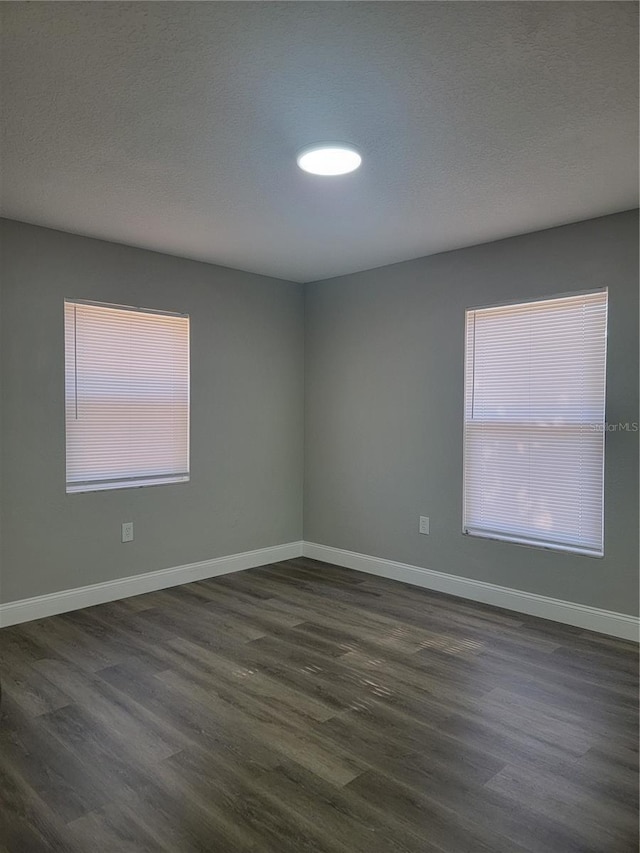 unfurnished room featuring a textured ceiling and dark hardwood / wood-style flooring