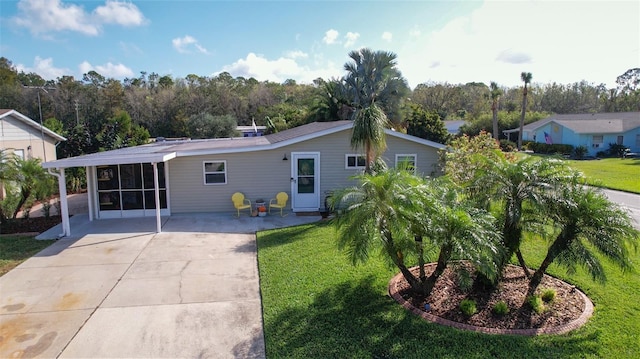 back of property featuring a yard, a sunroom, and a carport