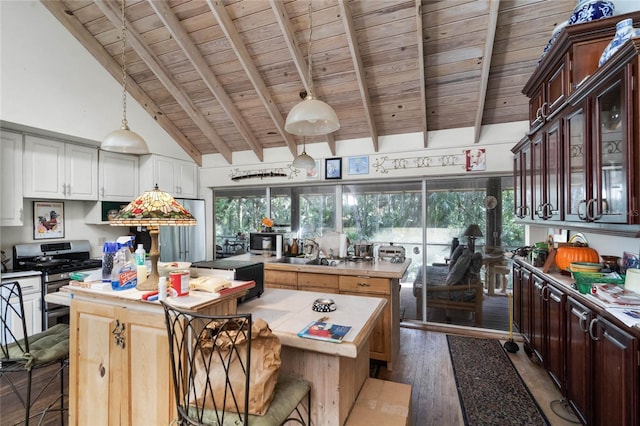 kitchen with stainless steel gas range, a center island, dark hardwood / wood-style flooring, wooden ceiling, and beamed ceiling