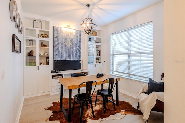 office space featuring light wood-style floors, baseboards, built in shelves, and a chandelier