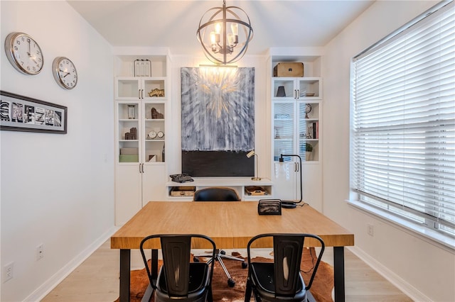 office area with a chandelier, baseboards, and light wood finished floors